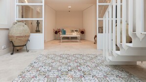Ein geräumiges Zimmer mit einem gemusterten Teppich, einem weißen Sofa und einer dekorativen Vase.