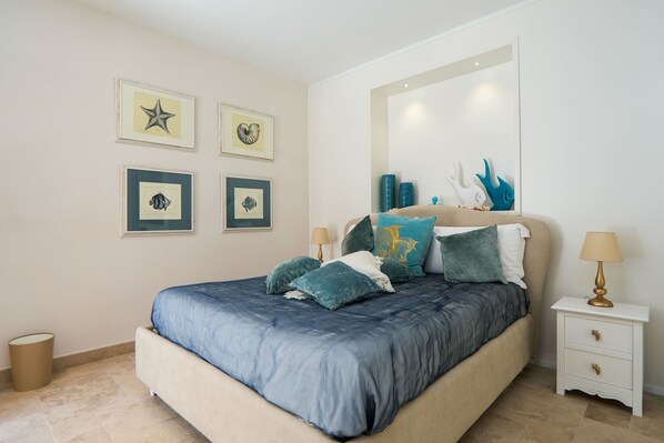 A bedroom with a bed, bedside tables, and wall art.