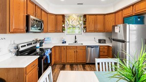 A kitchen with wooden cabinets, a stainless steel refrigerator, a microwave, and a dishwasher. - Downtown OC Townhome! - (B) (Ocean City)