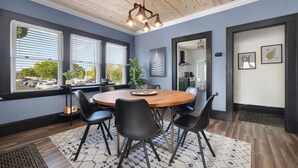 A modern dining area with a wooden ceiling, large windows, and a round table with chairs. - Walk to State Street - Remodeled Home (Bristol)