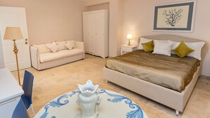 A bedroom with a bed, a sofa, a wardrobe, a table with a decorative item, and a lamp. - Marina Homes Standard 2 (Syracuse)