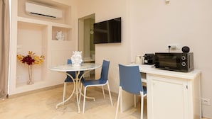 A compact kitchen with a microwave, a small cabinet, and a dining area with a table and chairs. - Marina Homes Standard 2 (Syracuse)