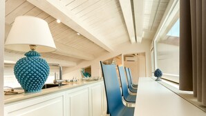 Une cuisine moderne avec des meubles blancs, une chaise bleue et une lampe bleue originale.