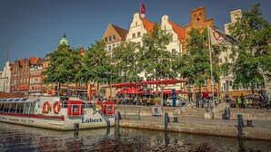En båt med namnet ”Lübeck” lade till vid en kaj, och i bakgrunden såg man en rad byggnader.
