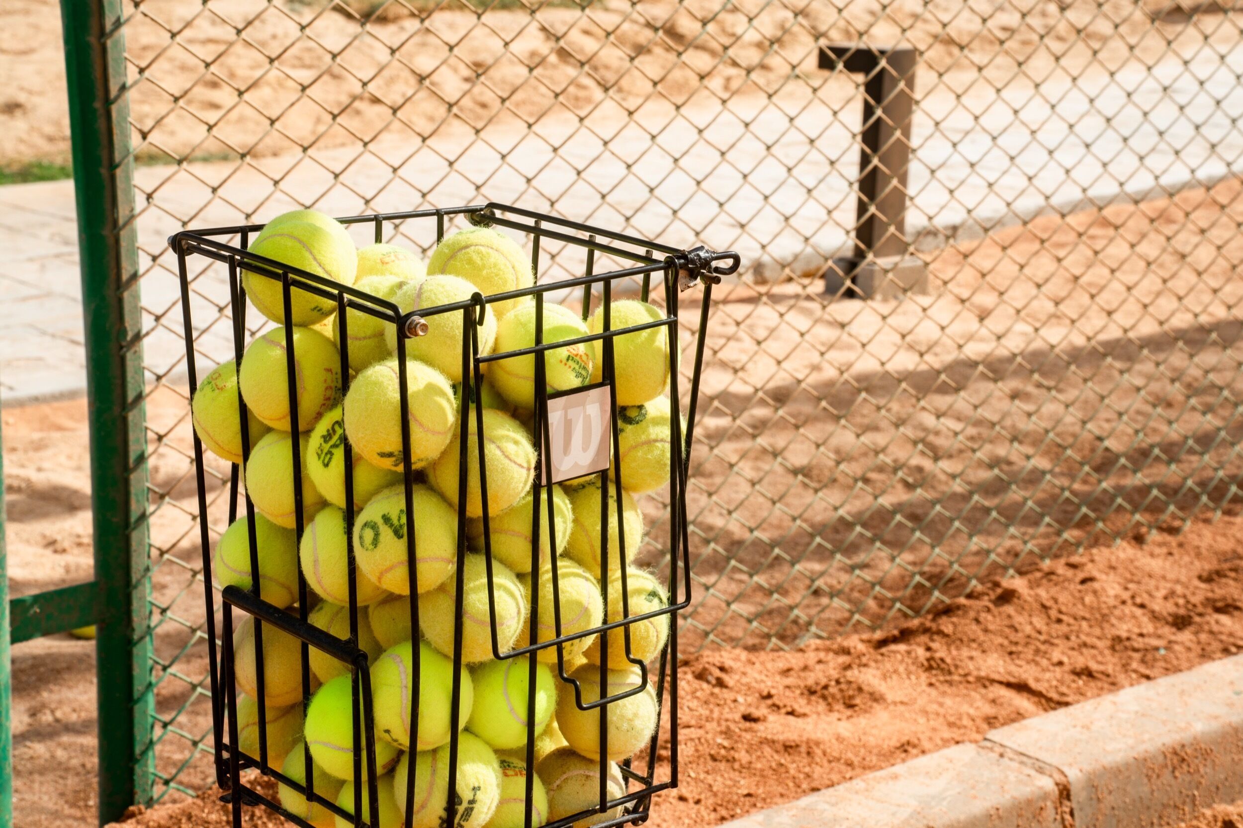 A metal cage filled with yellow tennis balls.