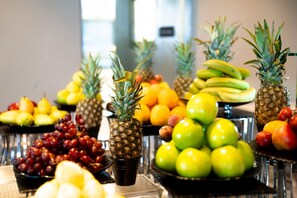 A variety of fruits displayed on a table, including pineapples, bananas, apples, and grapes.