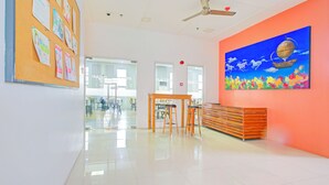 A bright, modern interior with a corkboard displaying notices, a wooden bench, and a colorful painting on the wall. - Collection O Metro Manila near University Belt formerly 1318 Residences (Manila)