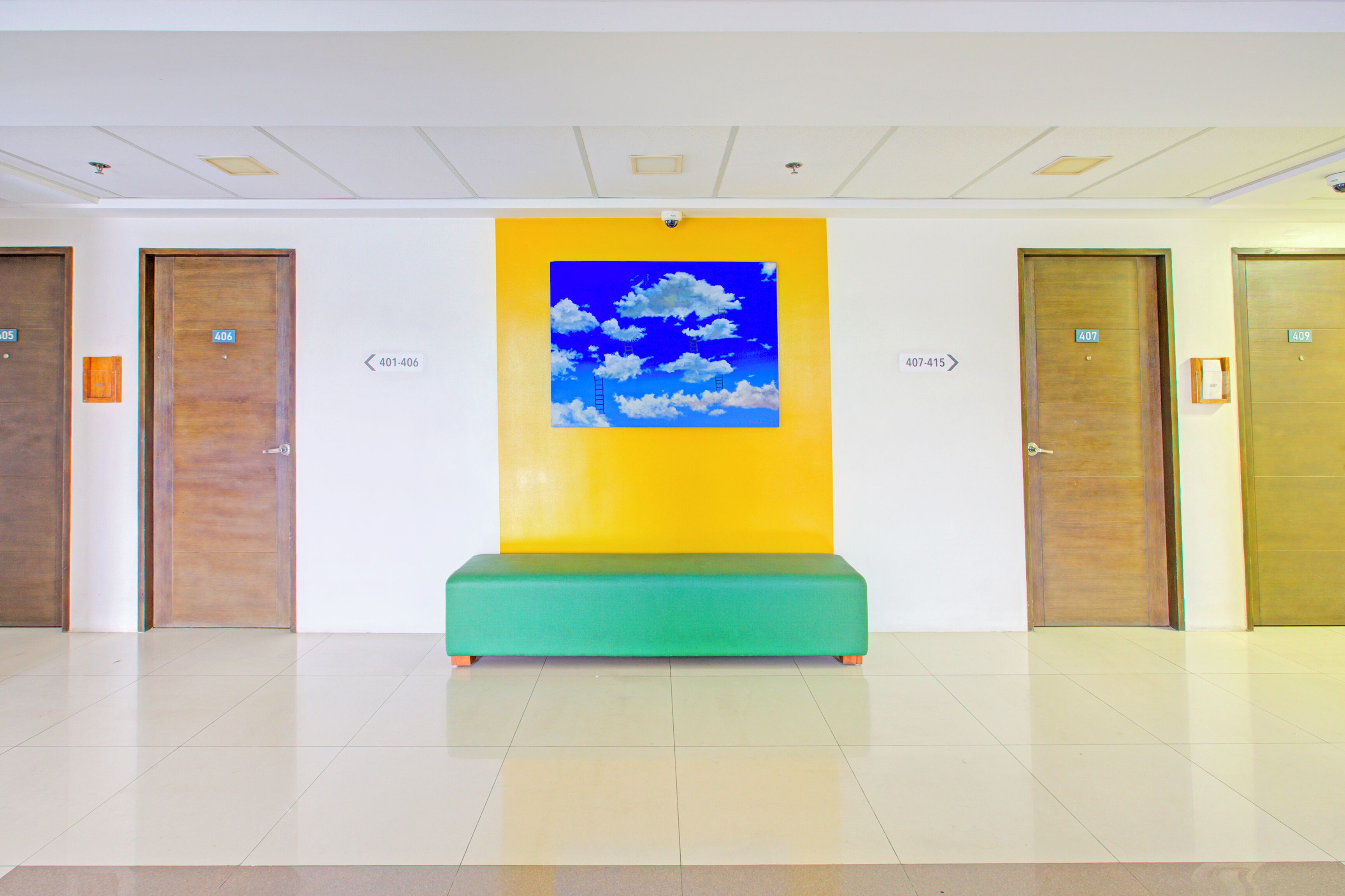 A lobby with a green bench, a yellow wall with a cloud painting, and doors labeled 401-406.