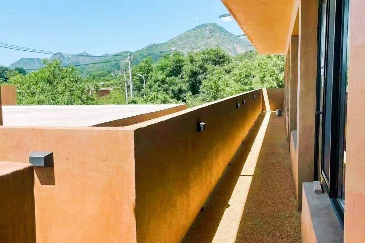 A balcony with a view of mountains and greenery.