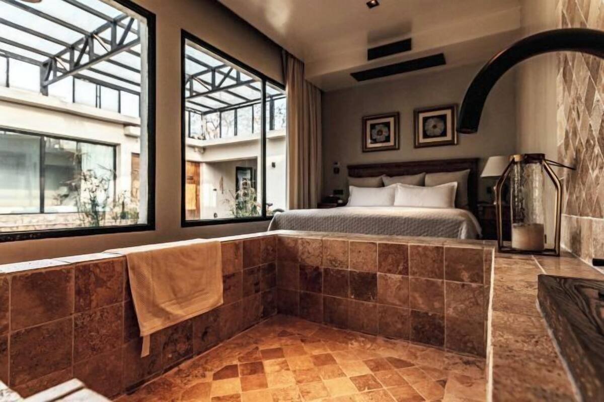 A modern bathroom with a large bathtub, a shower area, and a window providing natural light.