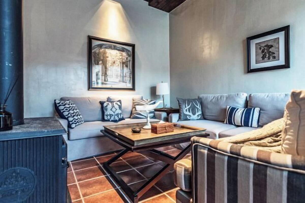 A living room with a sofa, a coffee table, a fireplace, and framed artwork on the walls.