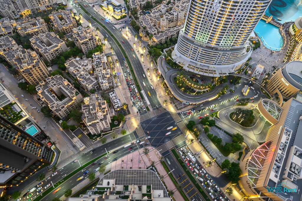 Vue aérienne d’une ville, avec un bâtiment aux courbes imposantes, un rond-point et des immeubles résidentiels et commerciaux environnants.