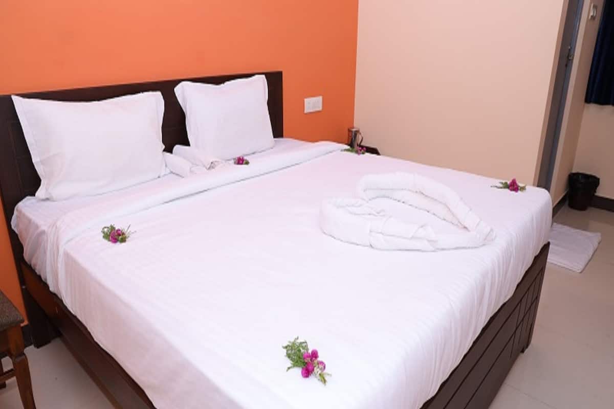 A neatly made bed with white linens, pillows, and a folded towel.