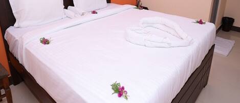 Un lit bien fait, avec des draps blancs, des oreillers et une serviette pliée.