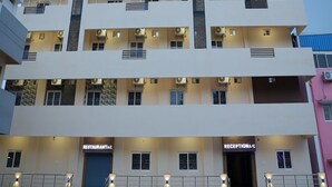 Un hotel de varios pisos con un diseño moderno, que cuenta con un restaurante y recepción en la planta baja.