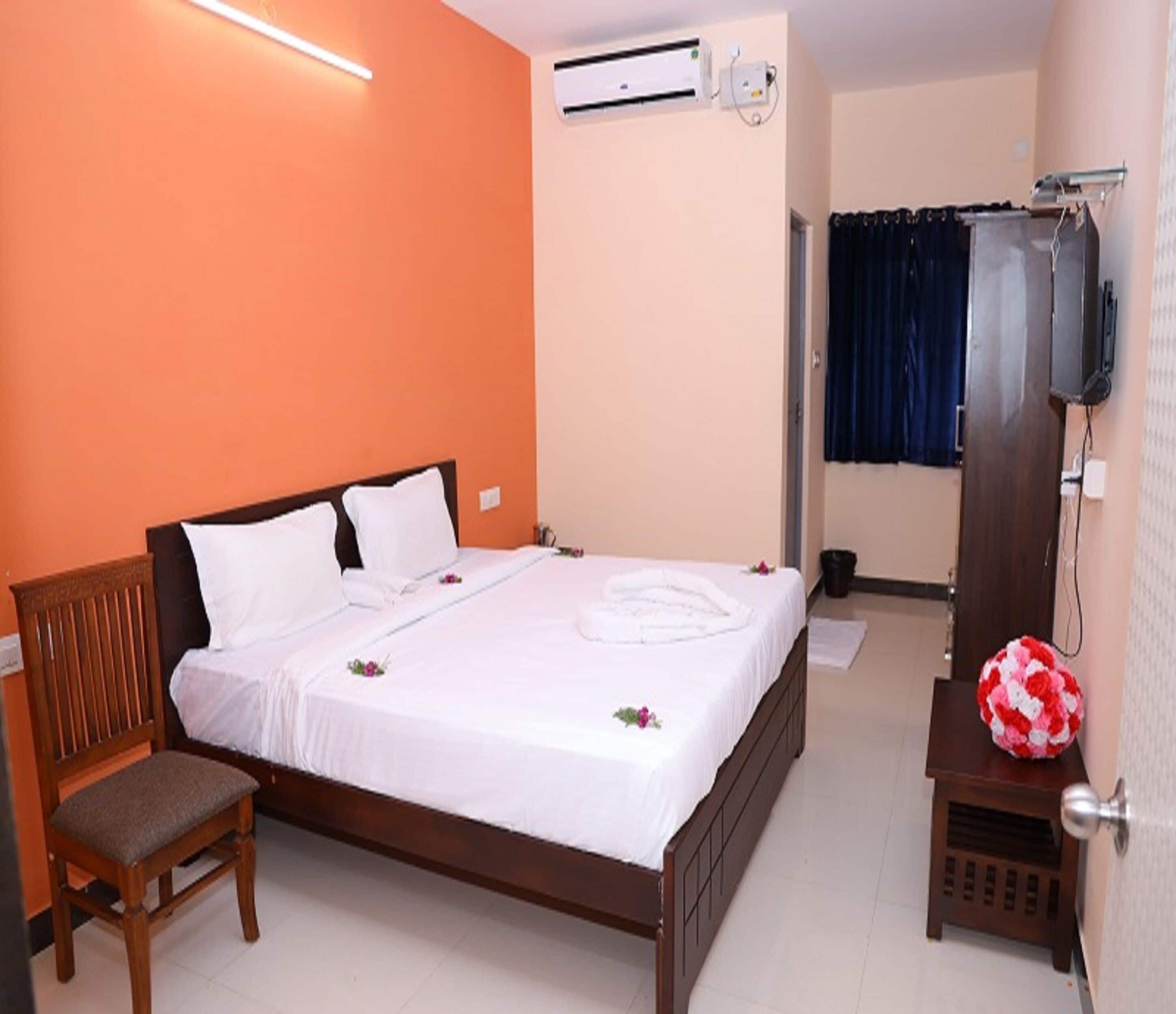 A bedroom with a wooden bed, a chair, an air conditioning unit, and a television.