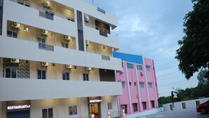 Un hotel de varios pisos con restaurante en la planta baja, zona de recepción y aparcamiento.
