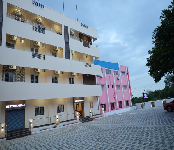 A multi-story hotel with a restaurant on the ground floor, a reception area, and a parking area. - Hotel Suryaa Grand (Vanur)
