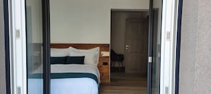 A bedroom with a bed, a wooden headboard, and a door leading to another room. - Casa NovecentoSei (Sonico)
