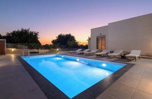 Ein Swimmingpool mit Liegestühlen und Blick auf den Sonnenuntergang.