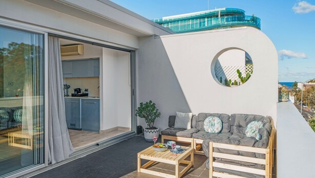 A modern balcony with a sofa, coffee table, and potted plant. - La Casa De Frida  (Bondi Beach)