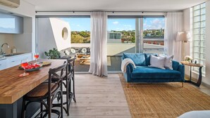 A modern apartment with a dining area, a blue sofa, and large windows offering a city view. - La Casa De Frida  (Bondi Beach)