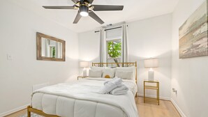 A bedroom with a bed, ceiling fan, window, and bedside lamps.