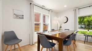 A dining area with a wooden table, six chairs, and a vase with feathers.