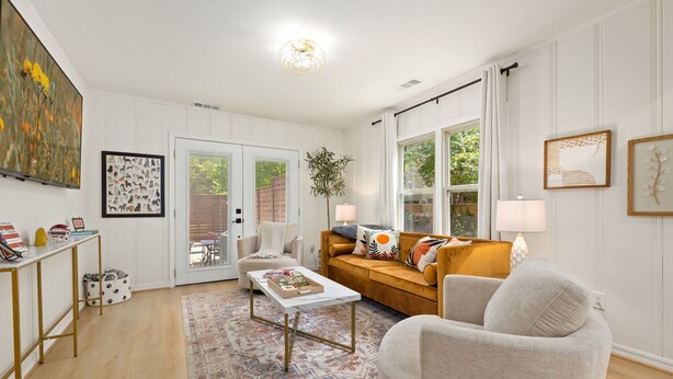 A living room with a sofa, armchair, coffee table, and a large window.