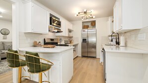A modern kitchen with white cabinetry, a stainless steel refrigerator, and a central island with bar stools.