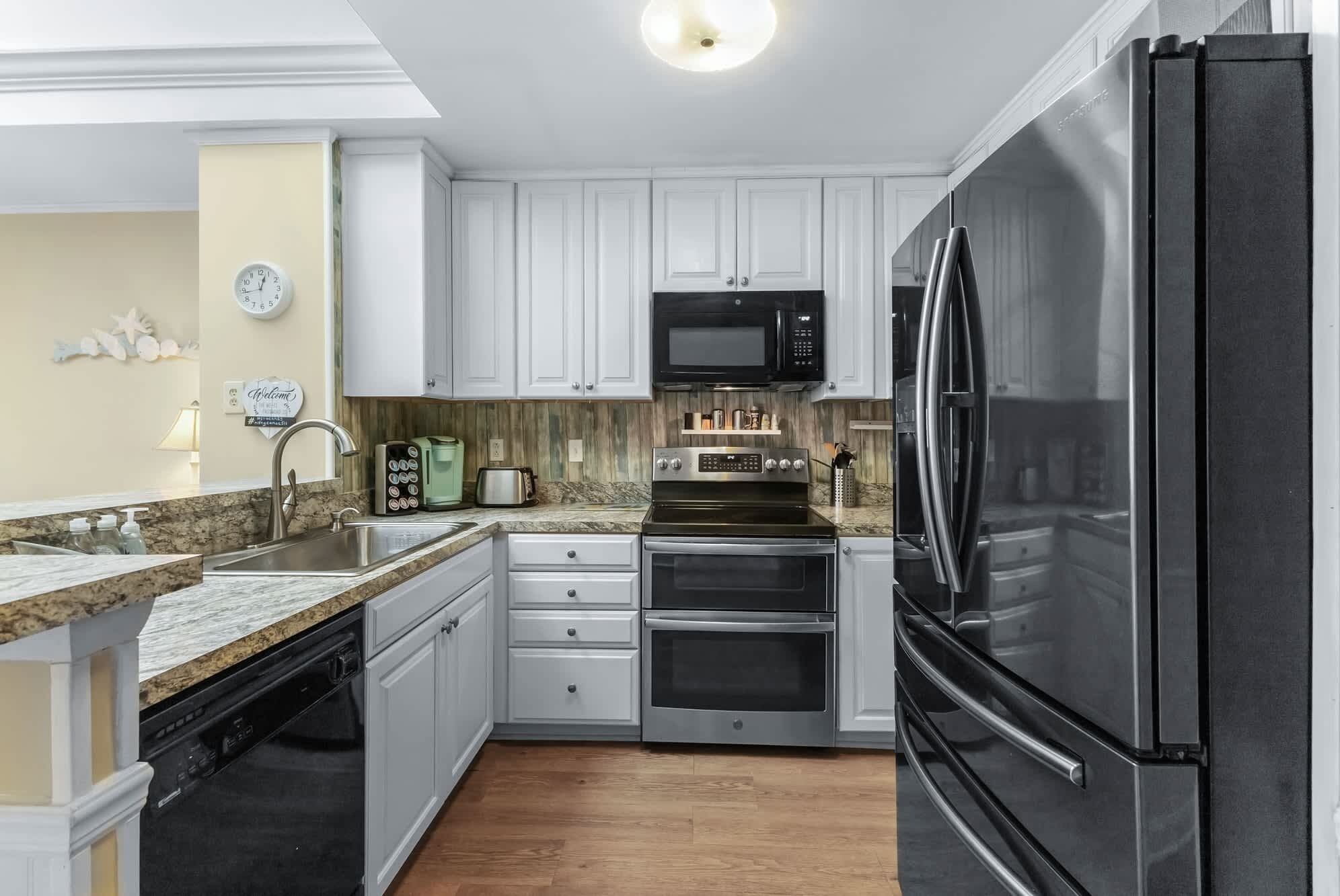 A modern kitchen with white cabinets, stainless steel appliances, and a granite countertop.
