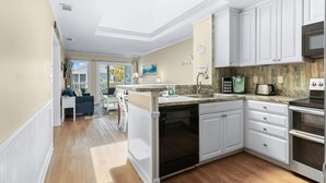 A kitchen with white cabinets, a black dishwasher, and a stainless steel oven. - Pelican Landing Unit 330 - Ocean view (Myrtle Beach)