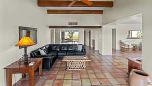 A spacious living area with a black leather sofa, a wooden coffee table, and a ceiling fan.