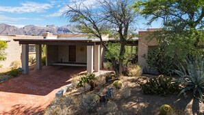 A desert-style building with a covered patio, surrounded by various cacti and desert plants.