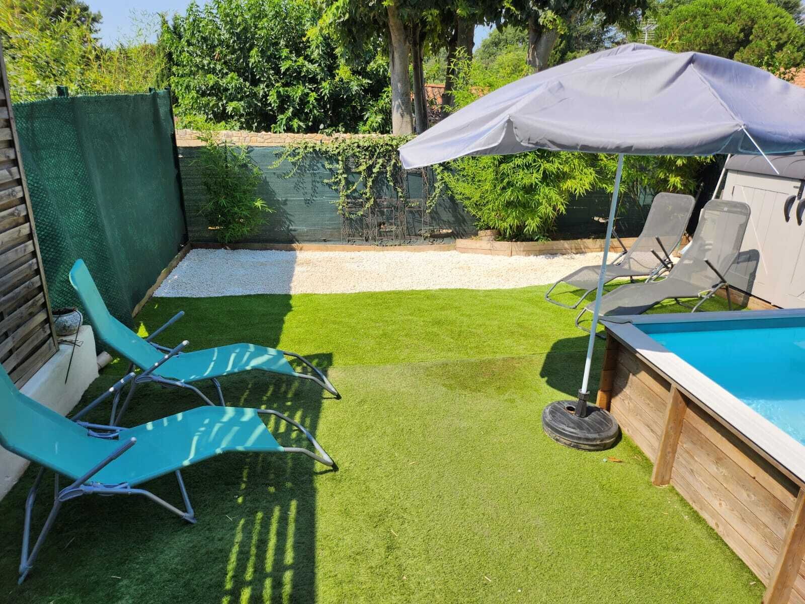 Een achtertuin met kunstgras, een zwembad en twee ligstoelen onder een zonnescherm.
