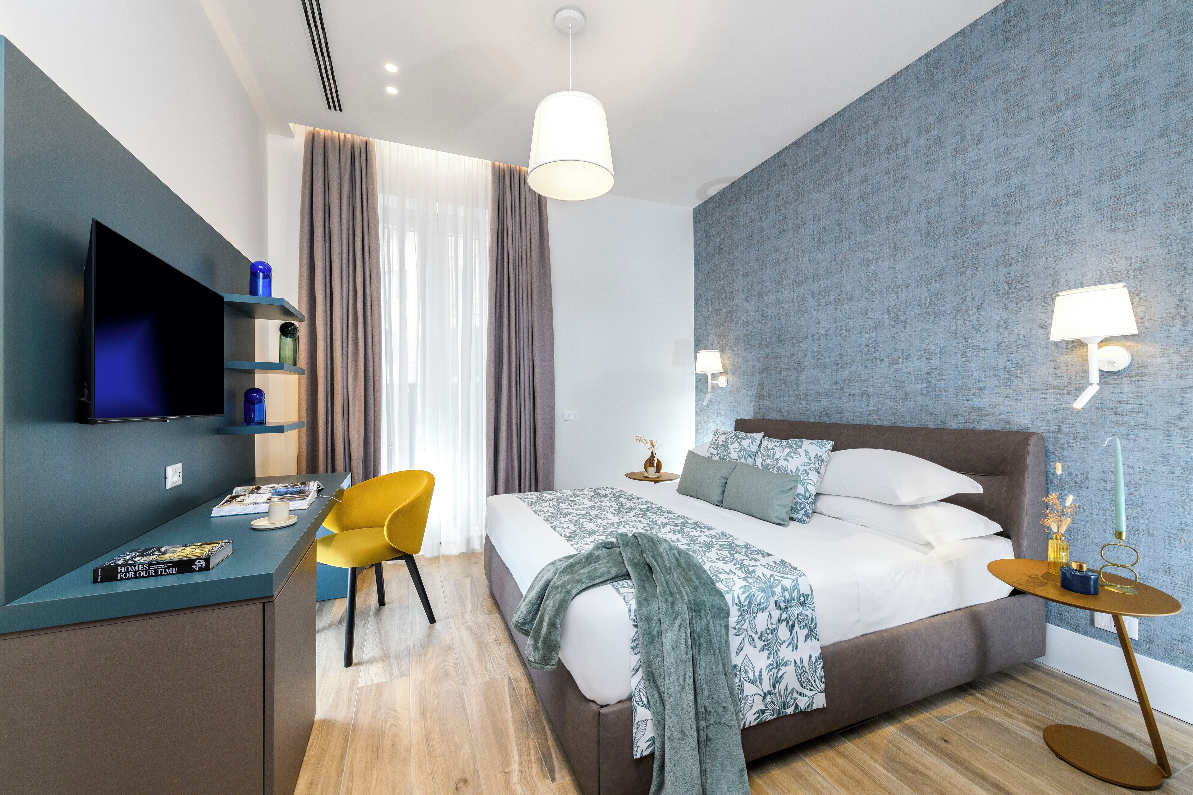 Une chambre d’hôtel moderne équipée d’un lit, d’un bureau, d’une chaise, d’une télévision et d’une lampe.