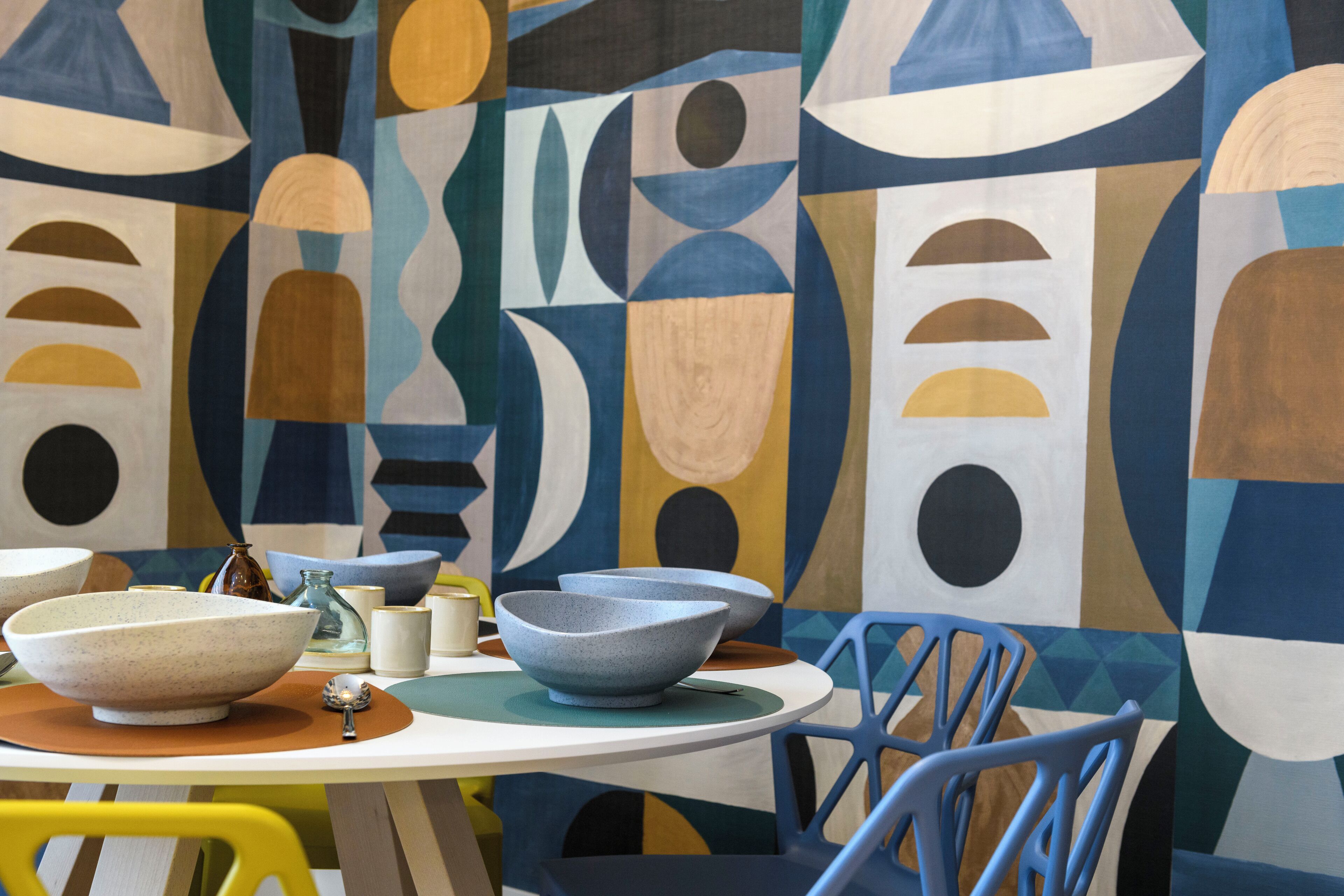 A dining area with a table set for two, featuring a white tablecloth and blue chairs.