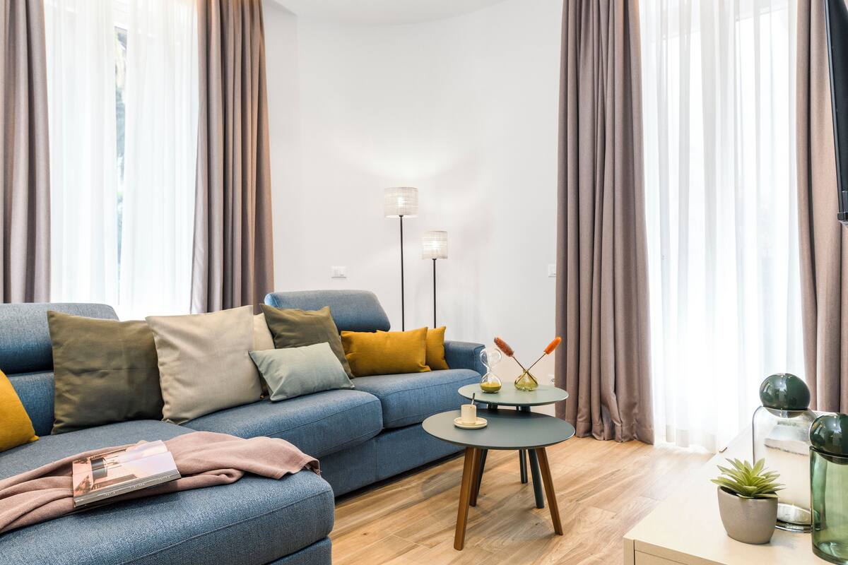 Ein modernes Wohnzimmer mit einem blauen Sofa, einem kleinen runden Tisch und einer Stehlampe.