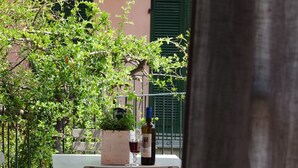 An outdoor seating area with a table and chairs, a bottle of wine, and a glass.
