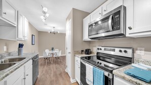 A modern kitchen with white cabinets, stainless steel appliances, and a granite countertop. - Stonecrest 620, 2Bd Apt I Free Parking I Pool (New Albany)