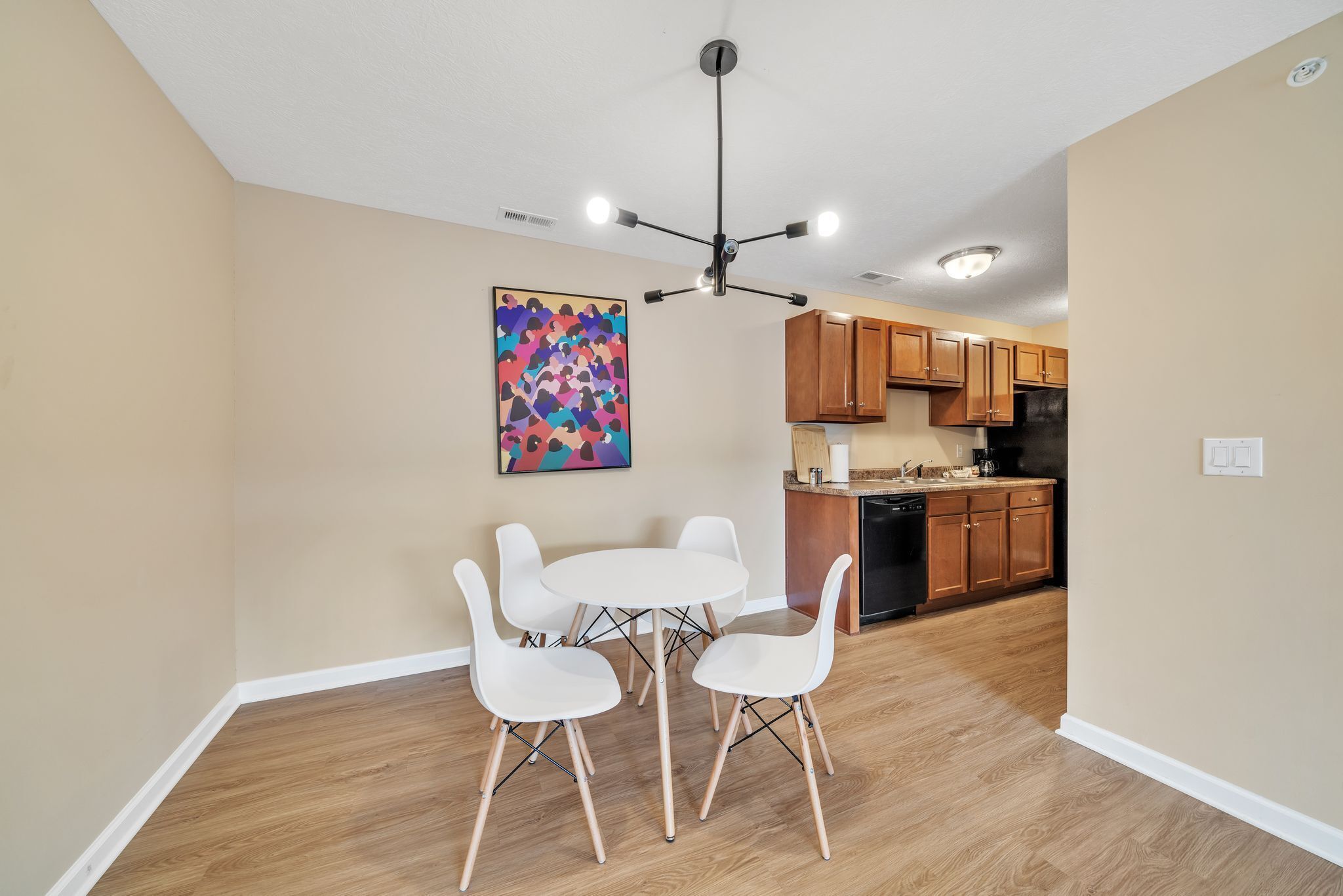 A modern kitchen with wooden cabinets, a black dishwasher, and a white countertop.