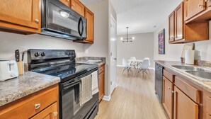 A modern kitchen with wooden cabinets, a black stove, and a granite countertop. - Stonecrest 701, 2Bd Apt I Free Parking I Pool (New Albany)