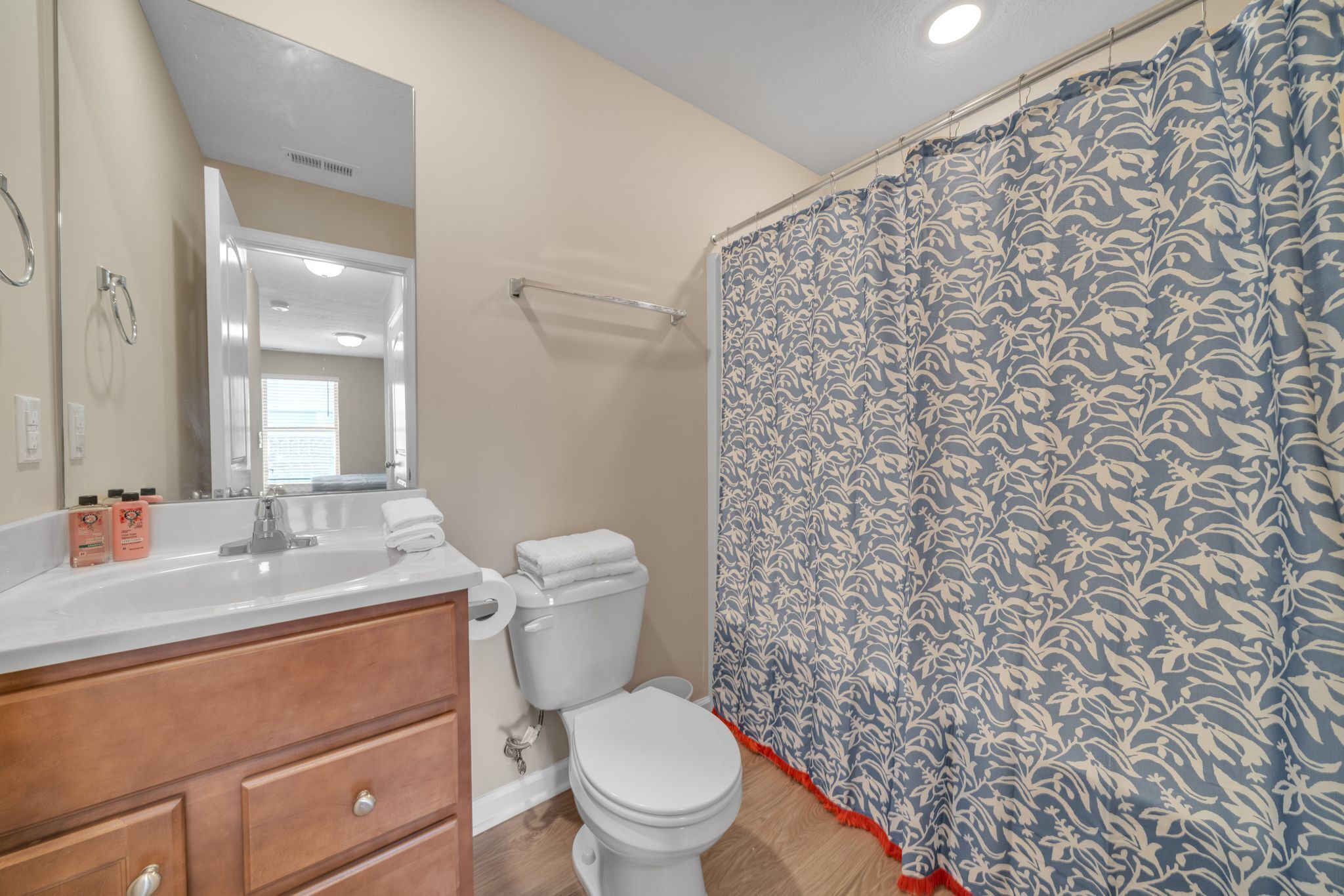 A bathroom with a white toilet, a sink with a mirror, and a shower curtain with a blue floral pattern.