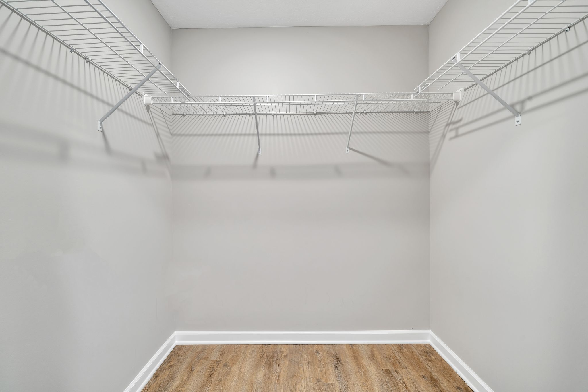 Un vestidor pequeño y vacío con suelo de madera y estantes de metal.