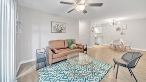 A modern living room with a beige sofa, a glass coffee table, and a patterned rug. - Stonecrest 713, 2Bd Apt I Free Parking I Pool (New Albany)
