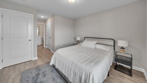 A bedroom with a bed, nightstands, a lamp, a door, and a hallway. - Stonecrest 716, 2Bd Apt I Free Parking I Pool (New Albany)