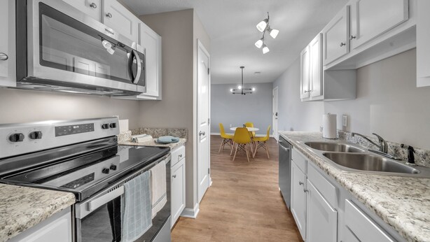 A modern kitchen with stainless steel appliances, granite countertops, and a dining area with yellow chairs. - Stonecrest 716, 2Bd Apt I Free Parking I Pool (New Albany)