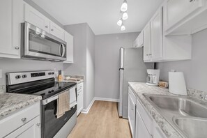 A modern kitchen with white cabinetry, a stainless steel refrigerator, a built-in oven, and a granite countertop. - Stonecrest 722, Modern 2Bd Apt I Parking I Gym (New Albany)