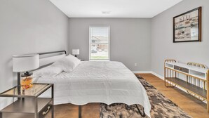 Une chambre à coucher moderne avec un lit, une table de chevet, une lampe et un berceau.
