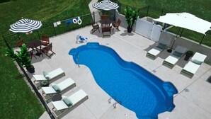 A rectangular swimming pool with lounge chairs and umbrellas, surrounded by a fence and greenery. - Stonecrest 822, 2Bd Apt I Free Parking I Pool (New Albany)